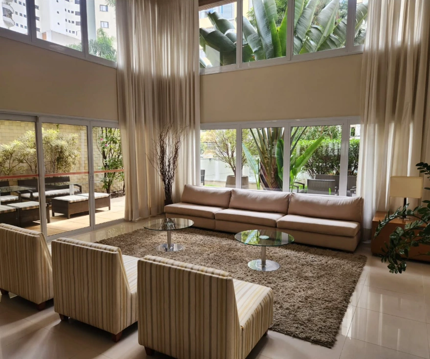 Sala com sofá claro, poltronas e grandes janelas, no portfólio da EF Clean